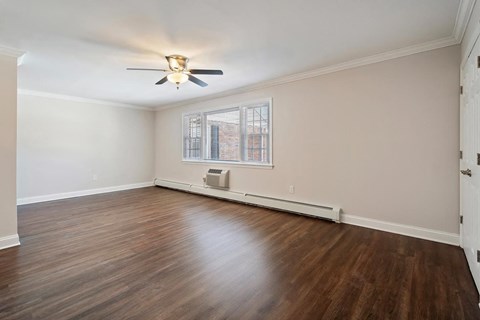 A room with a ceiling fan and a window with a view of a building outside.