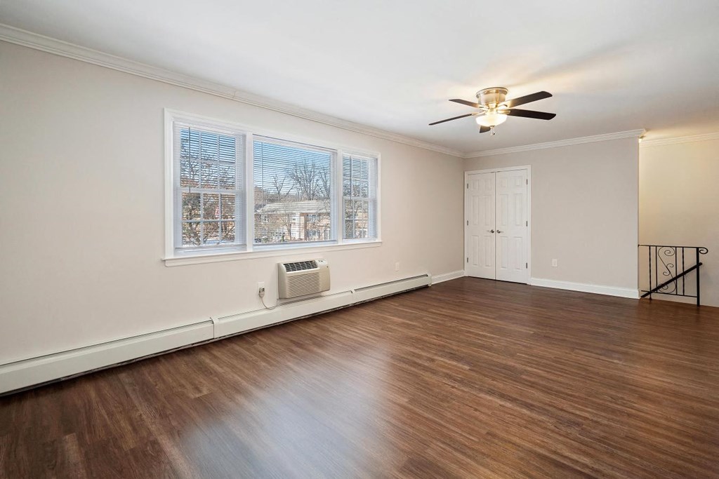 A room with a ceiling fan and a window with blinds.