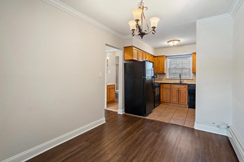 A kitchen with wooden floors and a black refrigerator.