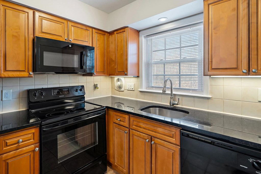 A kitchen with black appliances and wooden cabinets.