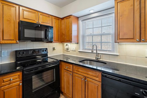 A kitchen with black appliances and wooden cabinets.