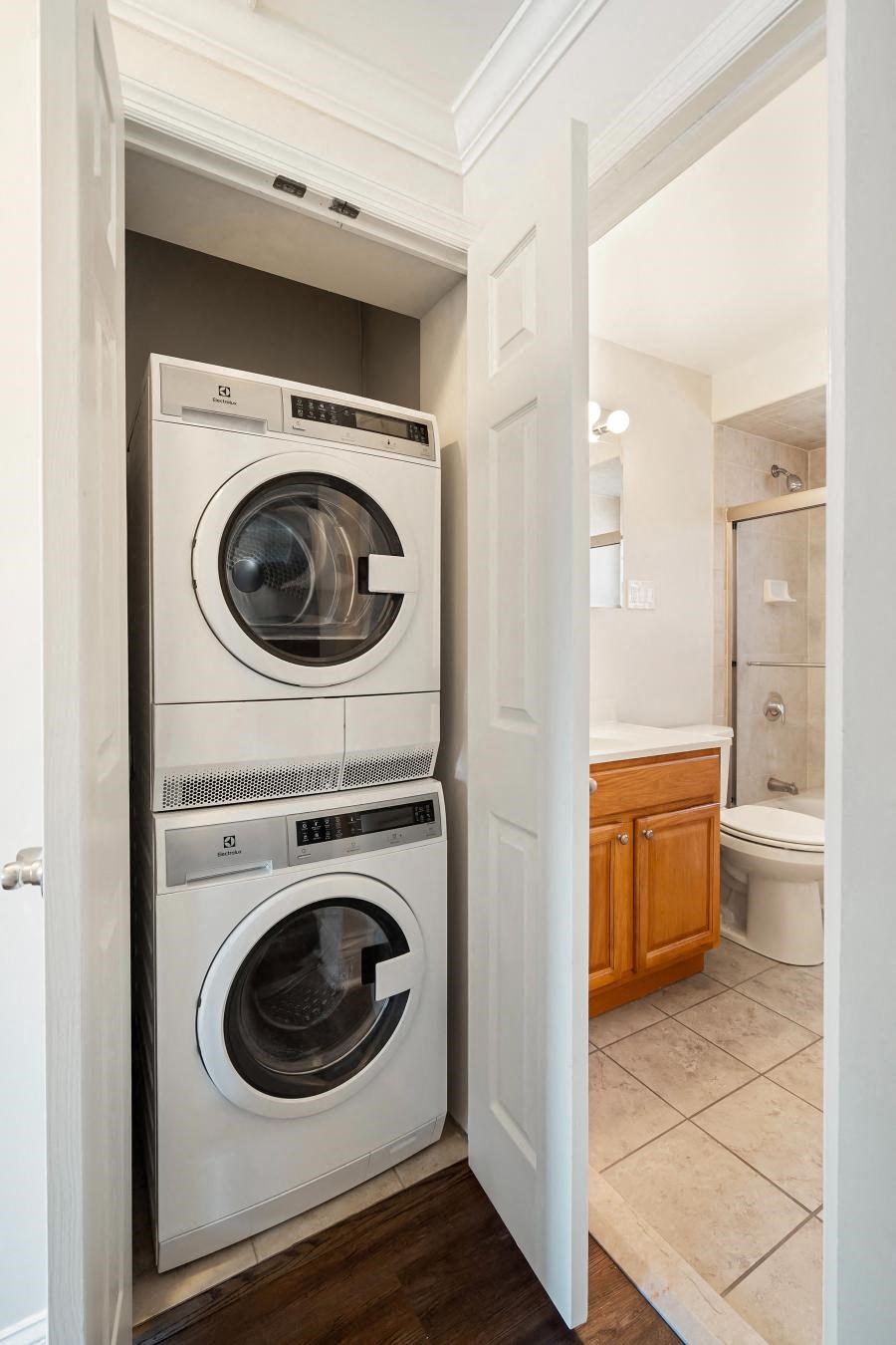 A white washer and dryer are stacked in a small laundry room.