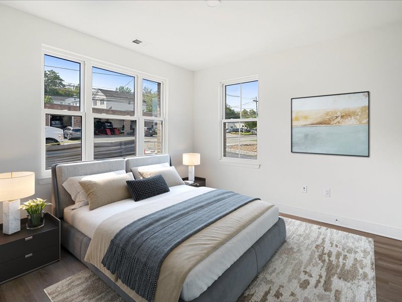 A bedroom with a large bed, a nightstand with a lamp, and a painting on the wall.