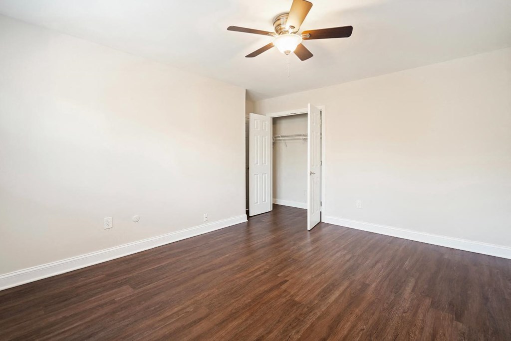 A room with a ceiling fan and wooden flooring.