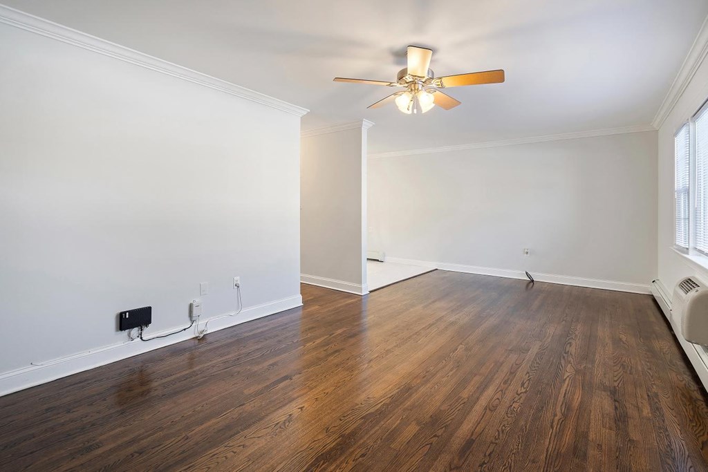 A room with a ceiling fan and wooden flooring.
