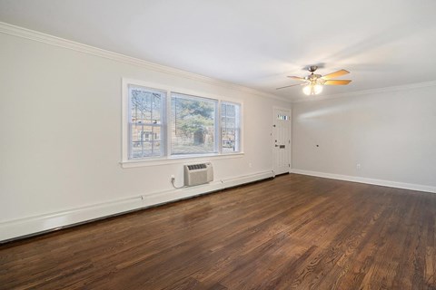 A room with a ceiling fan and a window with blinds.