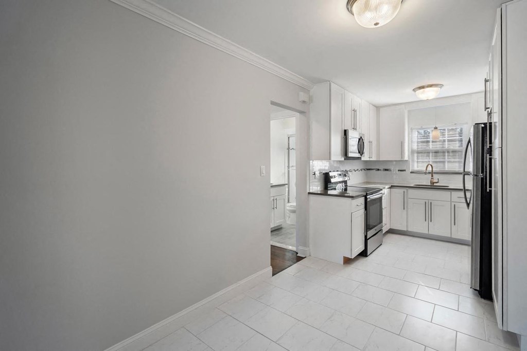 A kitchen with white cabinets and appliances.