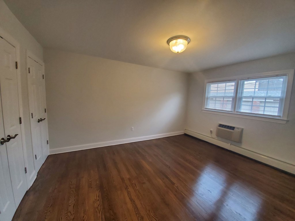 an empty living room with wood floors and a window