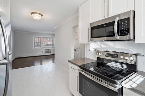 A modern kitchen with a stainless steel refrigerator, microwave, and oven.
