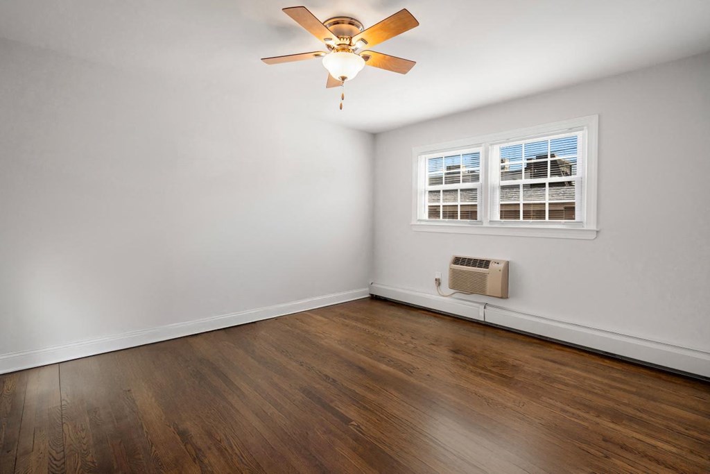 A room with a ceiling fan and a window with blinds.