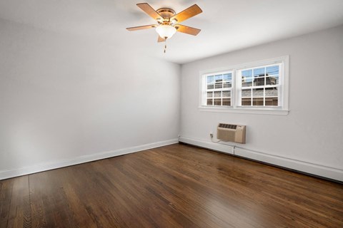 A room with a ceiling fan and a window with blinds.