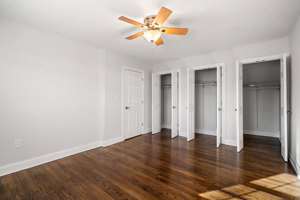A room with a ceiling fan and wooden floors.