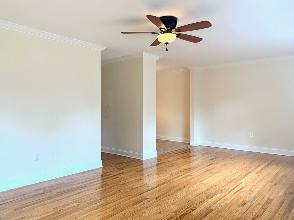 an empty living room with a ceiling fan