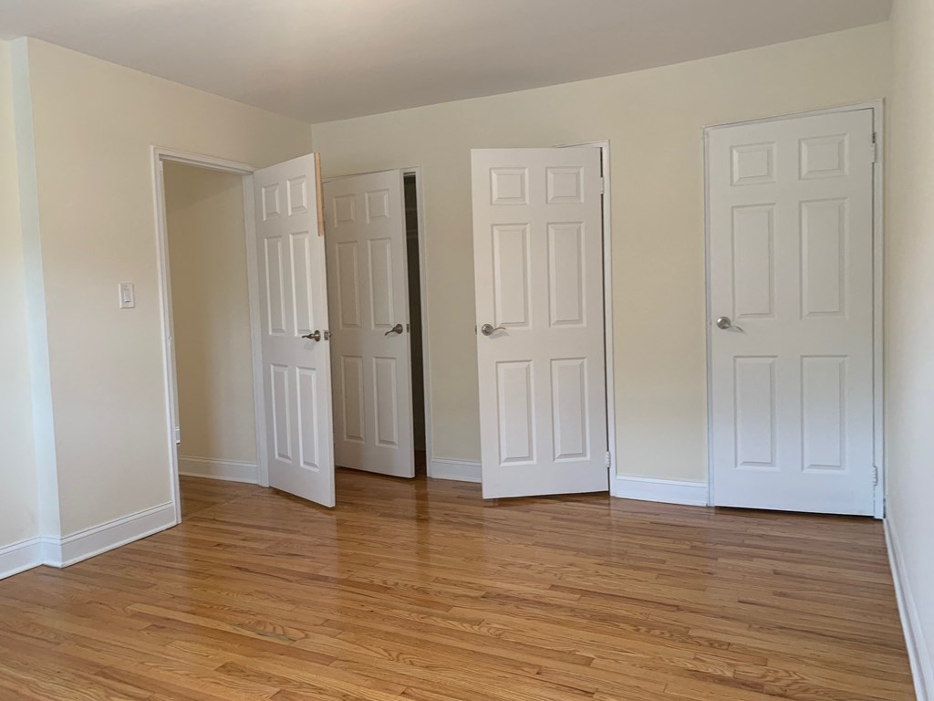 an empty room with three doors and a wood floor