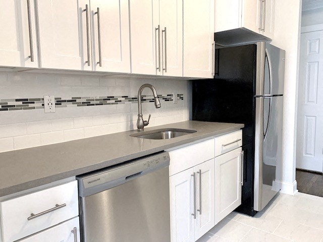 a kitchen with white cabinets and a stainless steel dishwasher