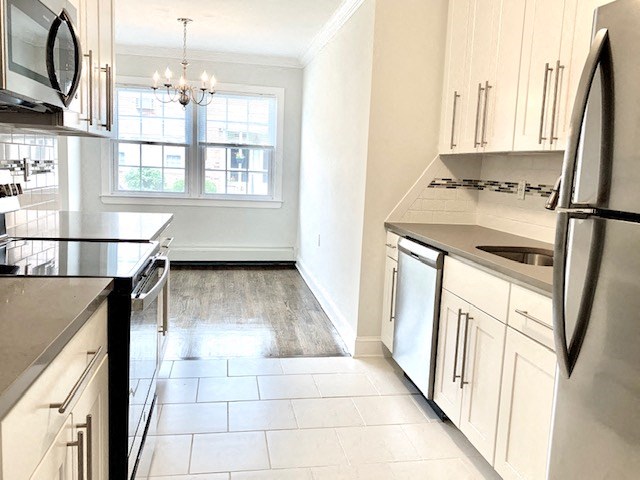 an empty kitchen with white cabinets and stainless steel appliances