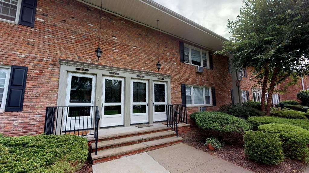 the front of a brick building with steps and a sidewalk