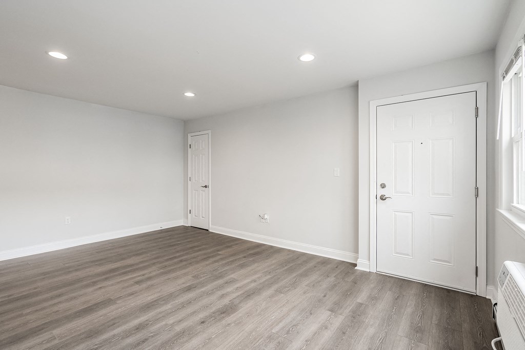 a bedroom with white walls and wood flooring and a door