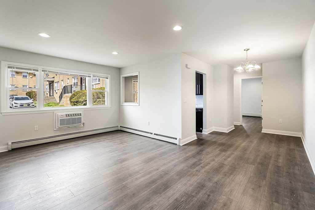 an empty living room with wood floors and a window