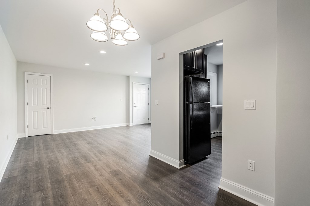 a renovated living room with a black refrigerator and white walls