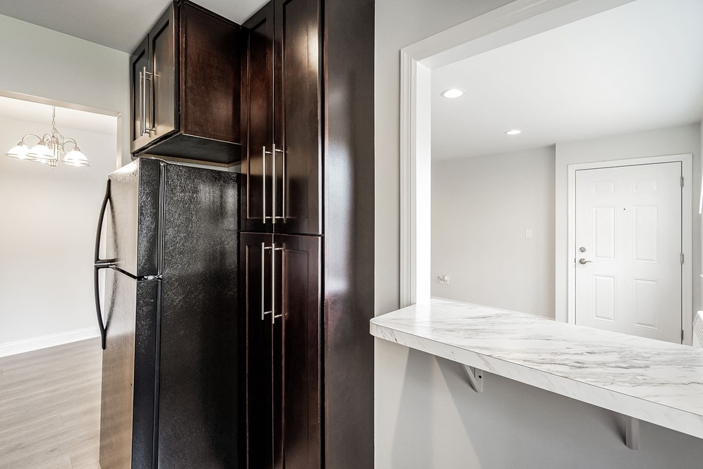 a kitchen with a refrigerator and a counter with a mirror