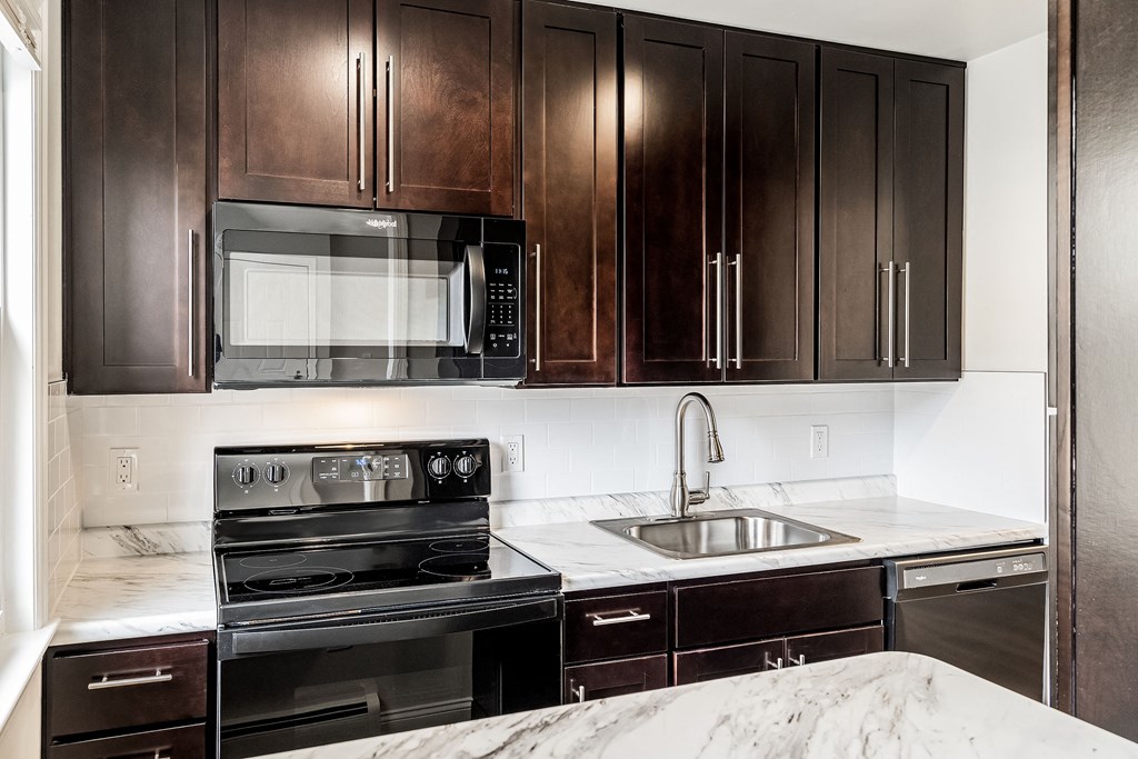 a kitchen with black appliances and dark wood cabinets