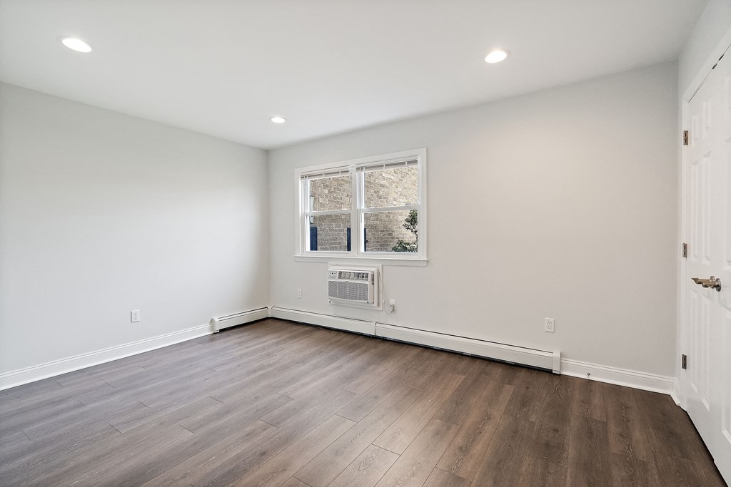 a living room with white walls and wood floors and a window