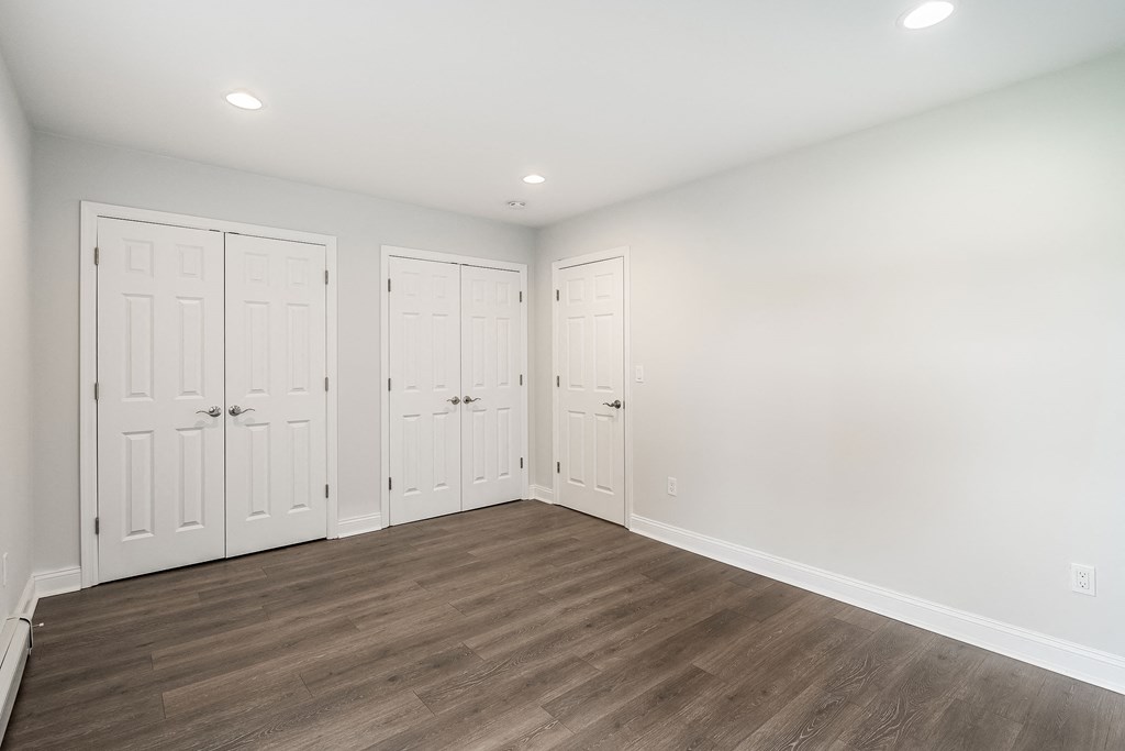 a bedroom with white walls and white closets and wood floors