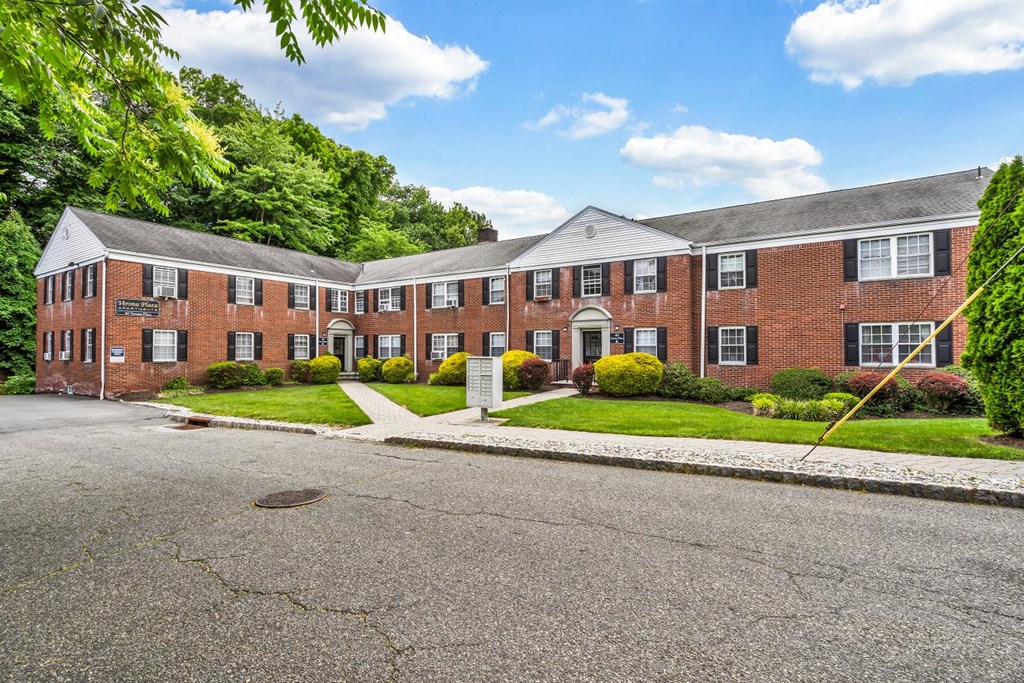 the front of a brick house with a driveway and grass