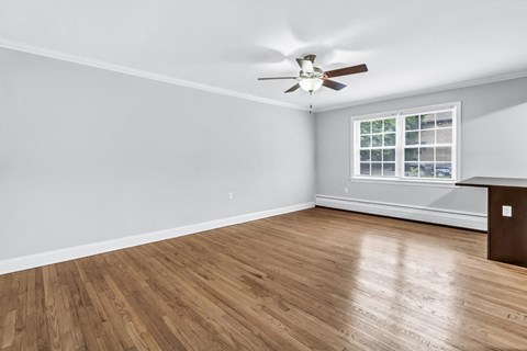 an empty living room with wood floors and a ceiling fan