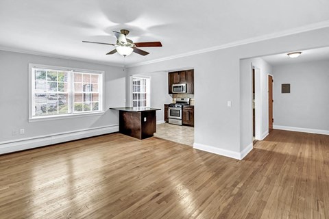an empty living room with a ceiling fan and a kitchen