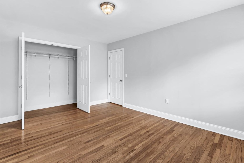 a bedroom with a closet and hardwood floors