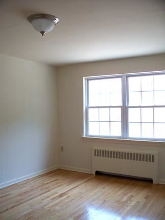 an empty room with a large window and wooden floors