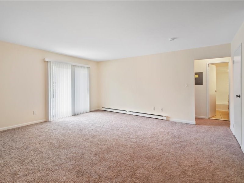 an empty living room with a door to a bathroom