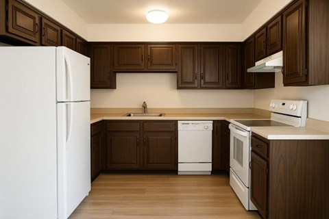 A white refrigerator stands in a kitchen with brown cabinets.
