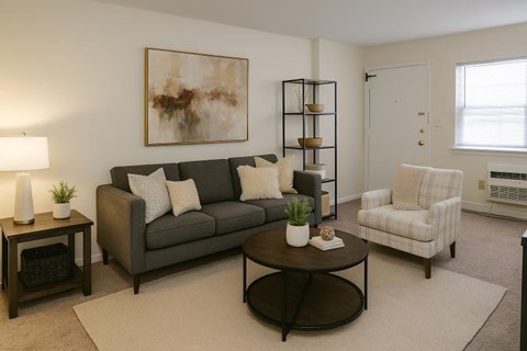 A living room with a grey couch, a white chair, and a coffee table.