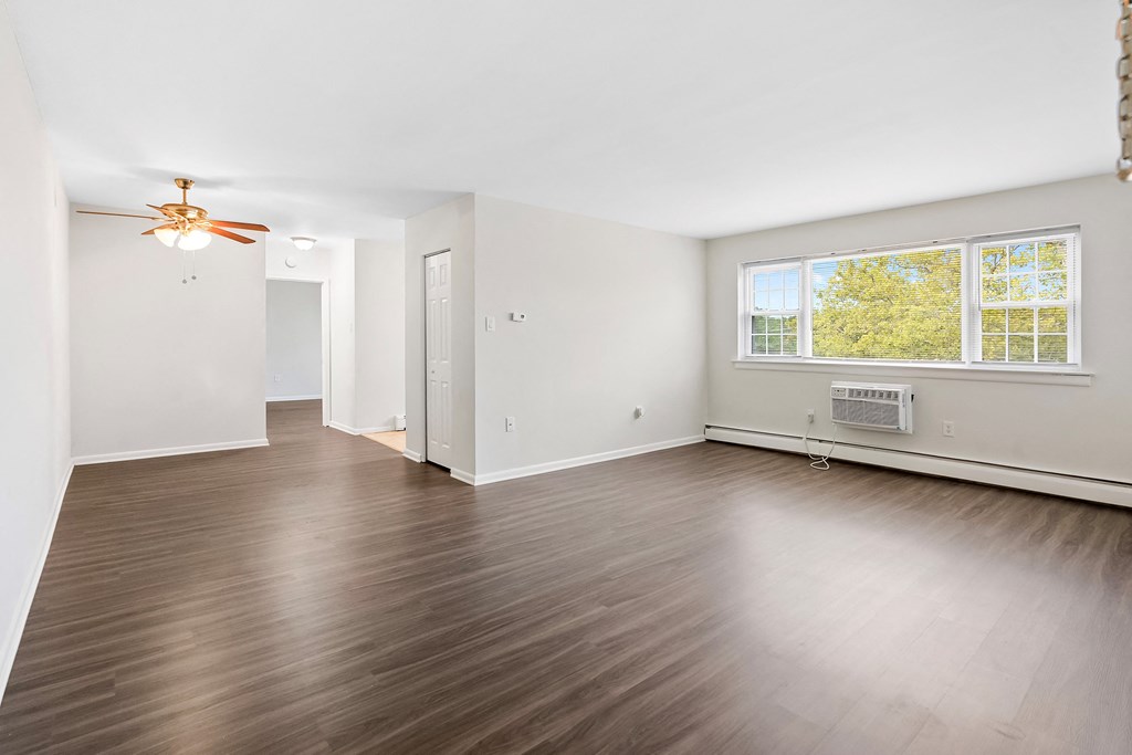 an empty living room with wood floors and a ceiling fan