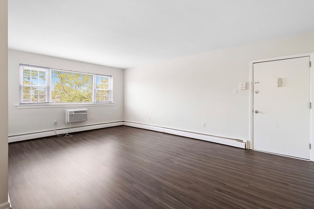 an empty room with white walls and wood floors and a window