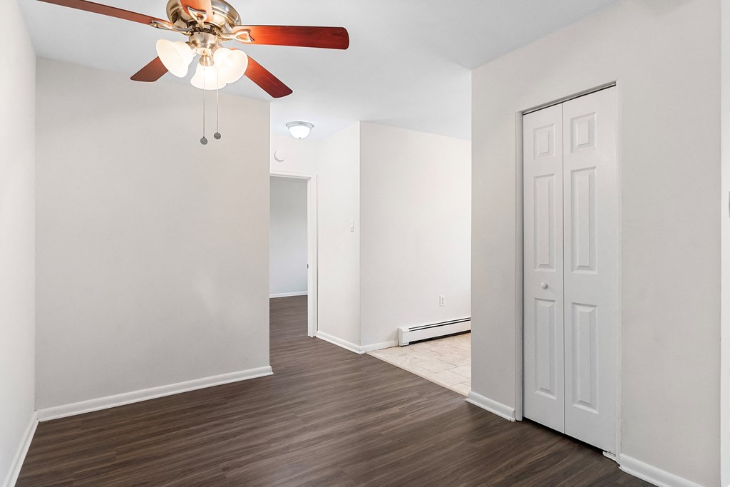 an empty living room with a ceiling fan and white walls