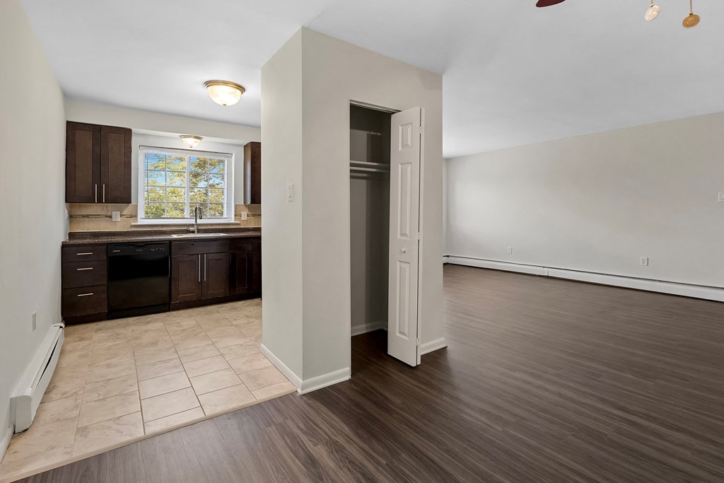 an empty kitchen and living room with wood flooring and white walls