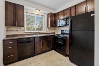 a kitchen with dark wood cabinets and a black refrigerator