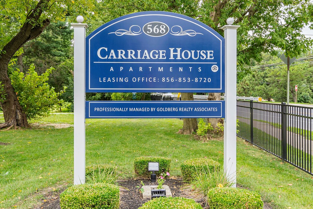 a sign that reads carriage house apartments lease office and fence
