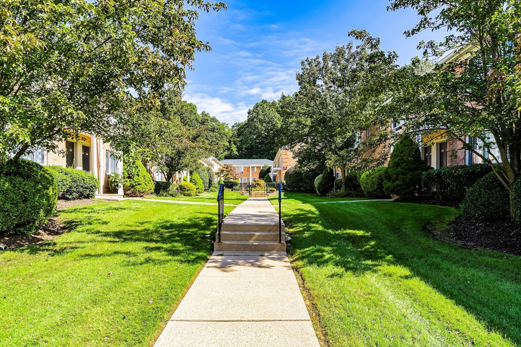 a sidewalk leading up to a house with trees and a gazebo