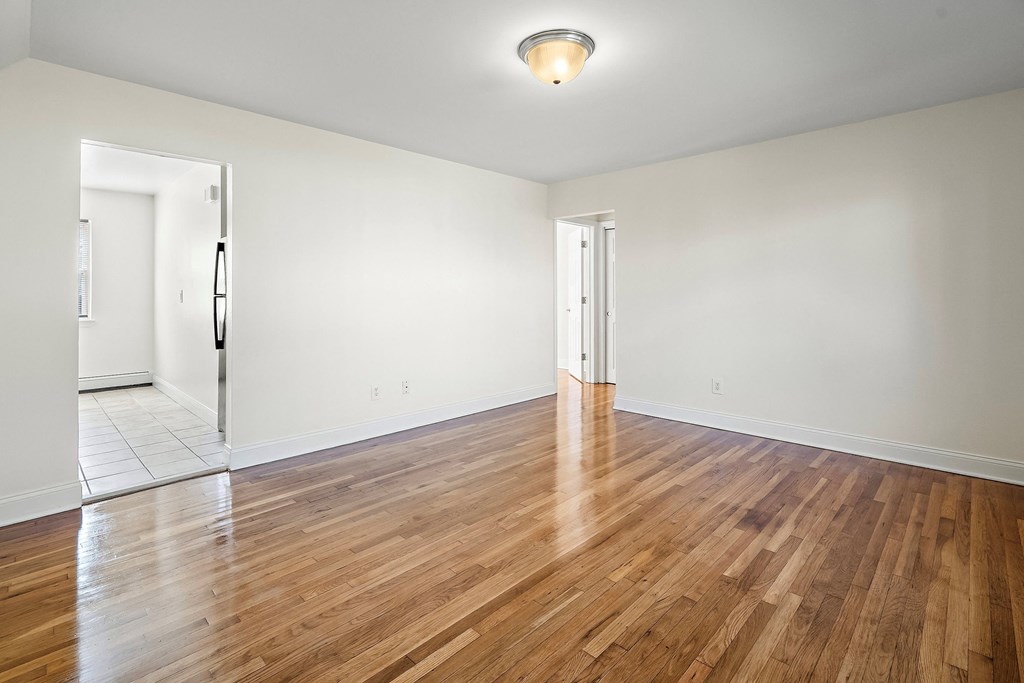 an empty living room with wood floors and white walls