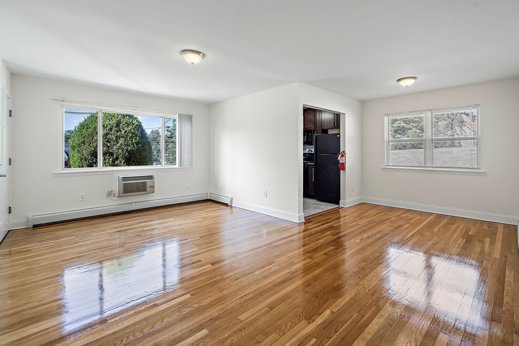 an empty living room with wood floors and a window