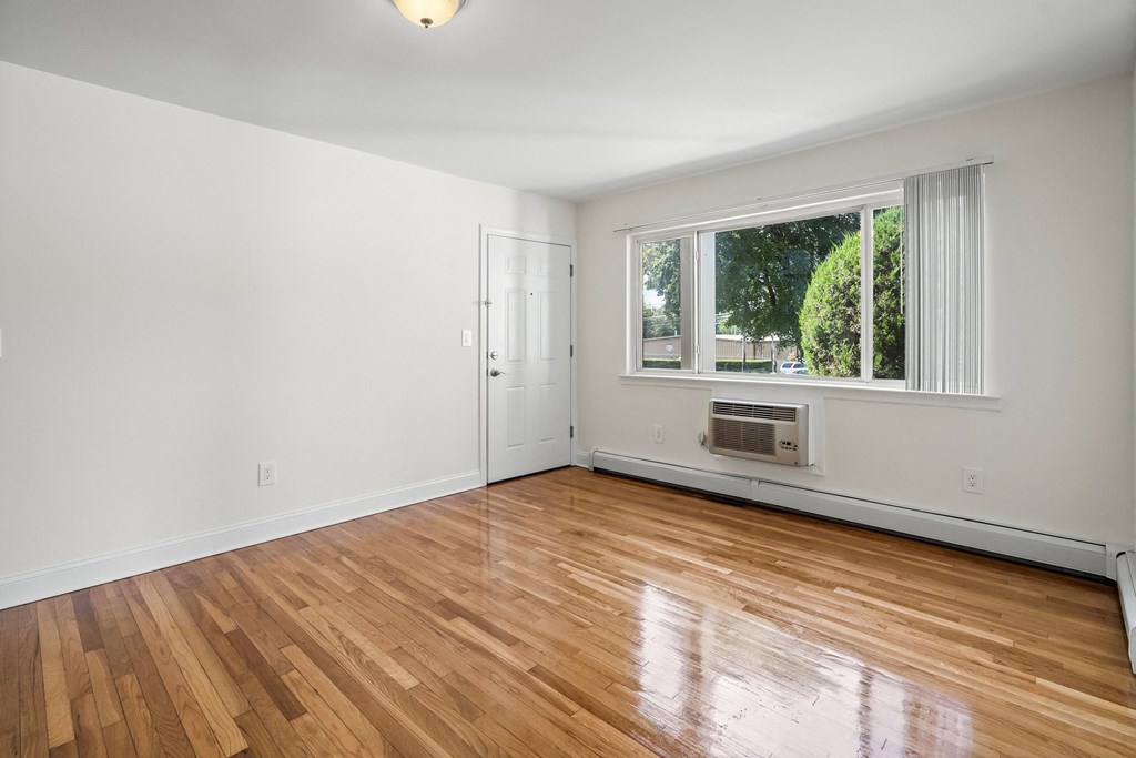 an empty living room with wood floors and a window