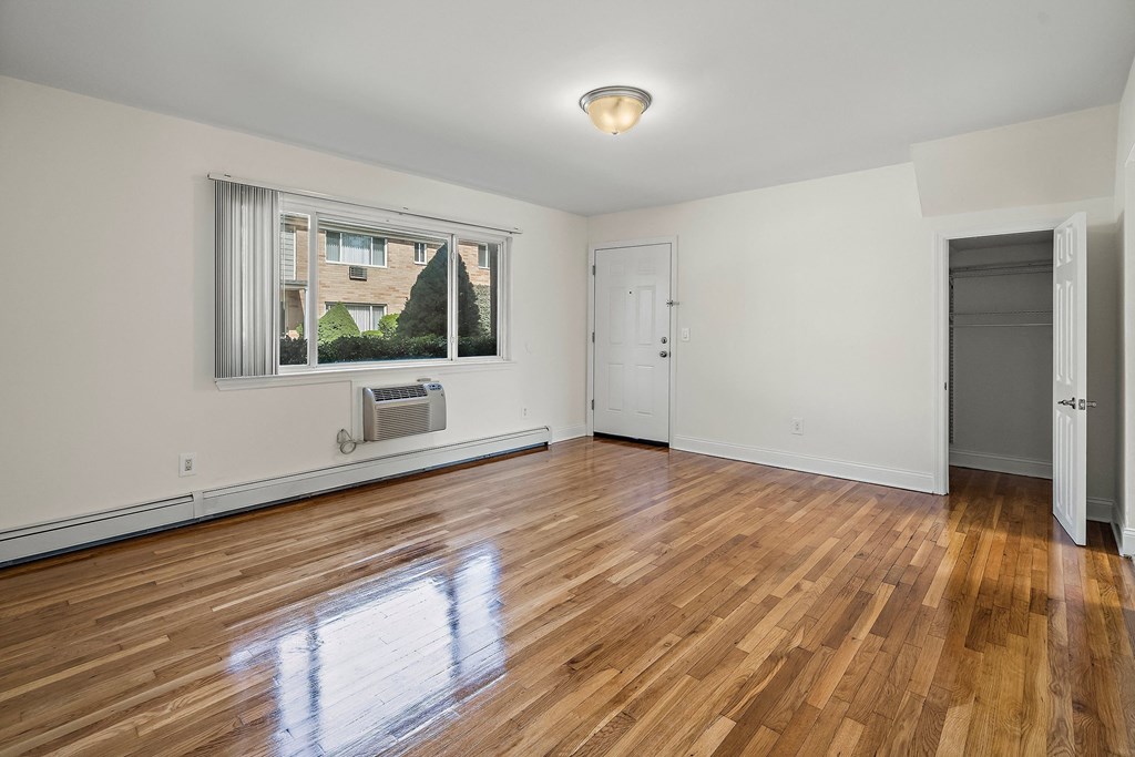 an empty living room with wood floors and a window