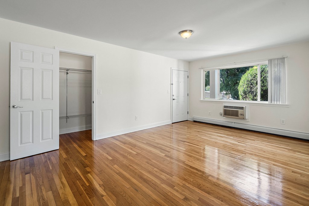 an empty living room with wood floors and a window