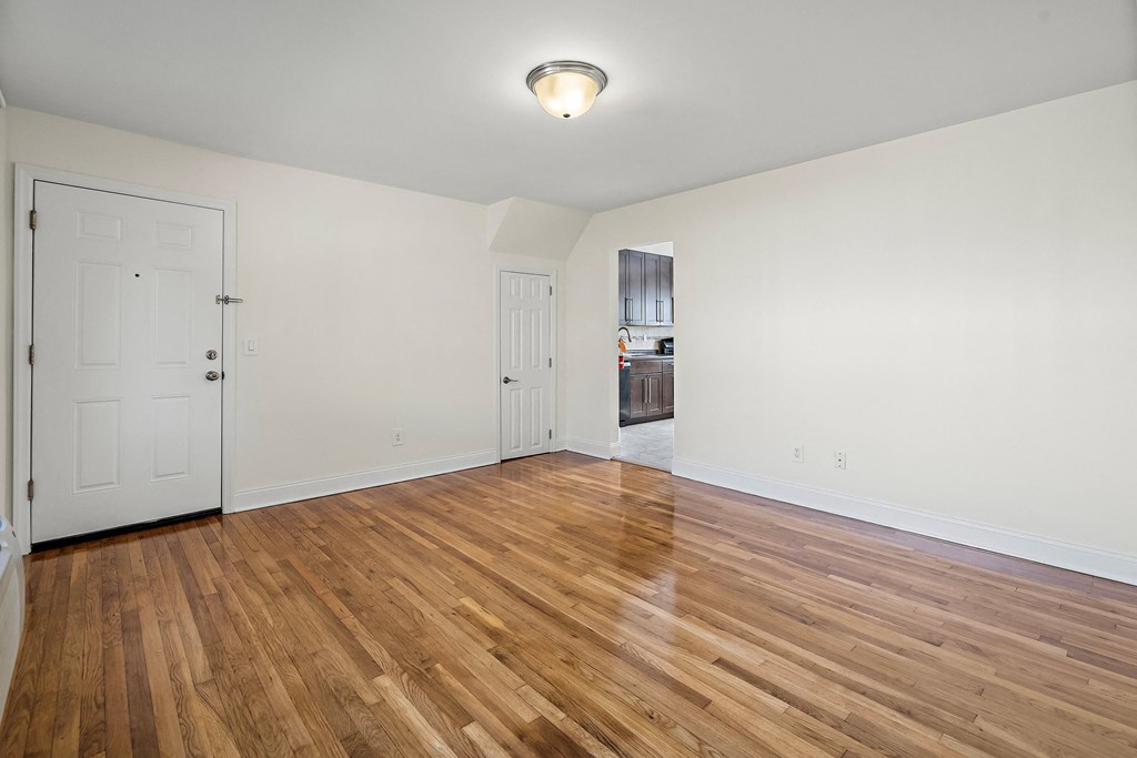 an empty living room with wood flooring and white walls