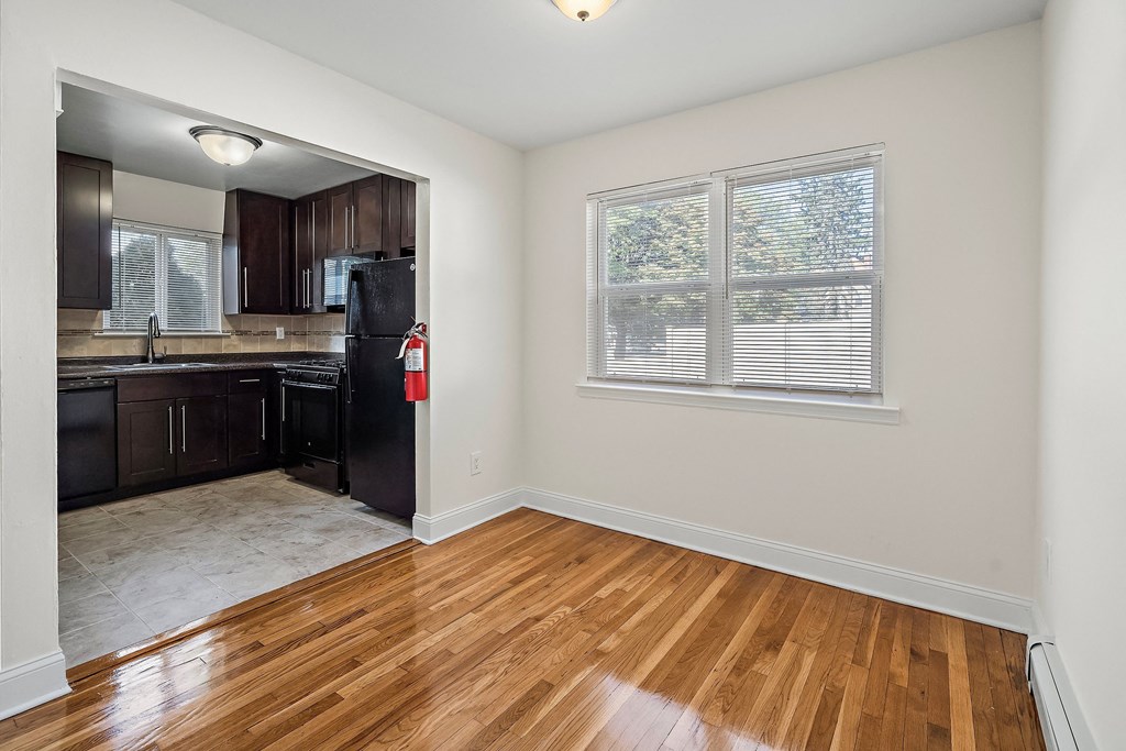 an empty kitchen with black appliances and wood floors